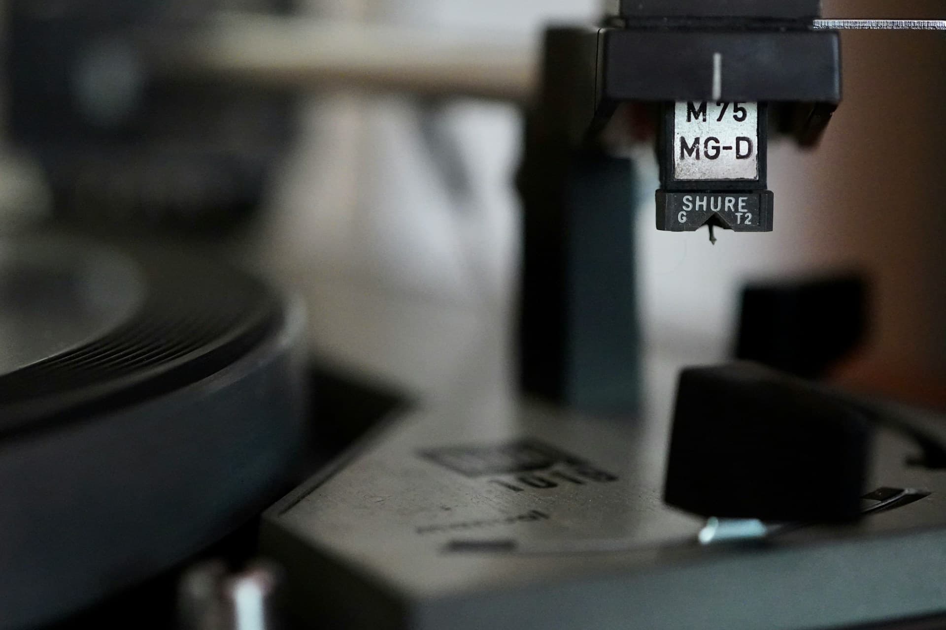 A turntable stylus rests in the groove of a spinning record
