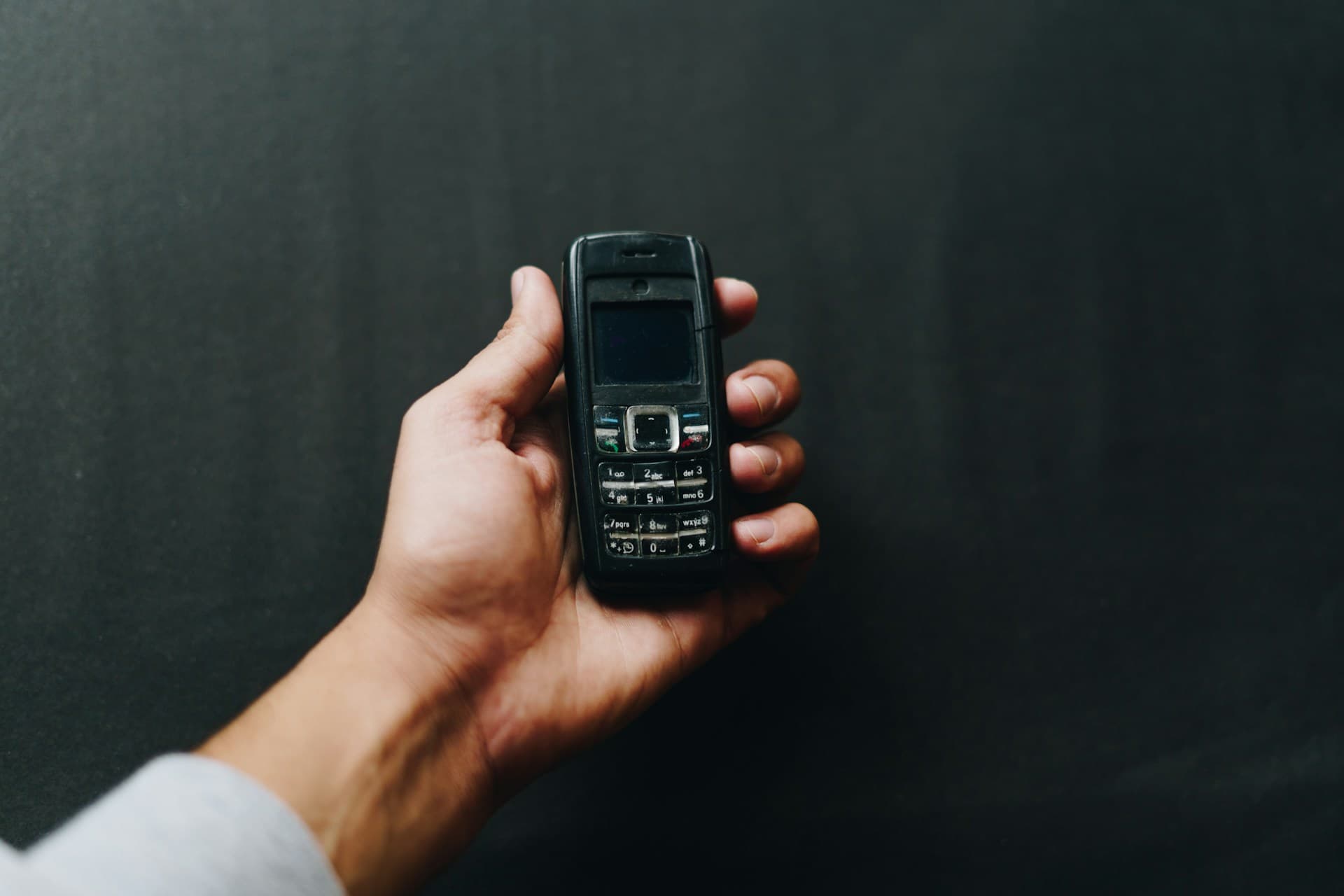 A black Nokia candy bar phone rests in an open hand