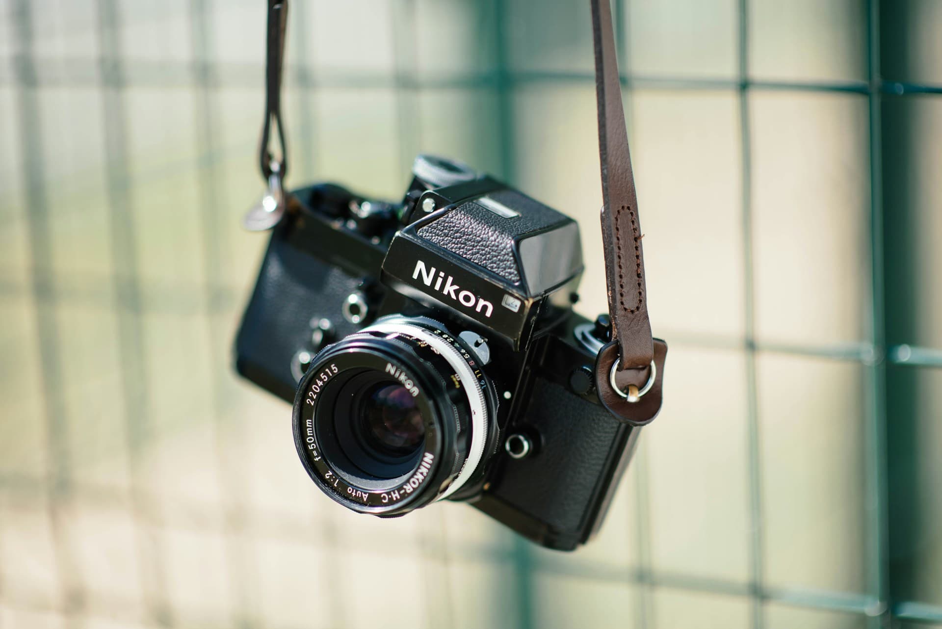 A classic Nikon SLR film camera sits on a dark surface in soft side light