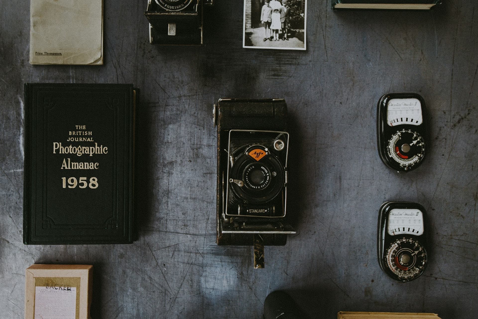 A flat lay of classic film cameras, lenses, and rolls of 35mm film on a desk